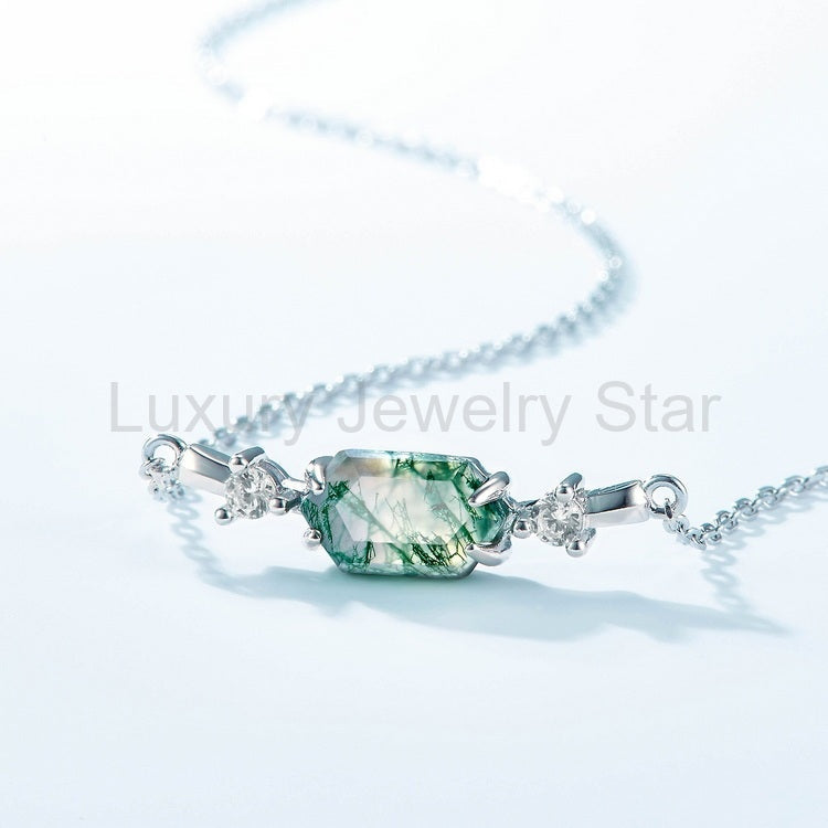 Close-up of a green hexagon center, prongs and two clear side accents on a necklace.