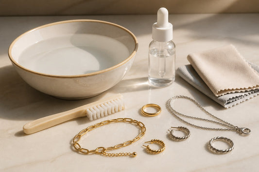 Bowl of water, small brush, cloths and jewelry arranged for a cleaning illustration.