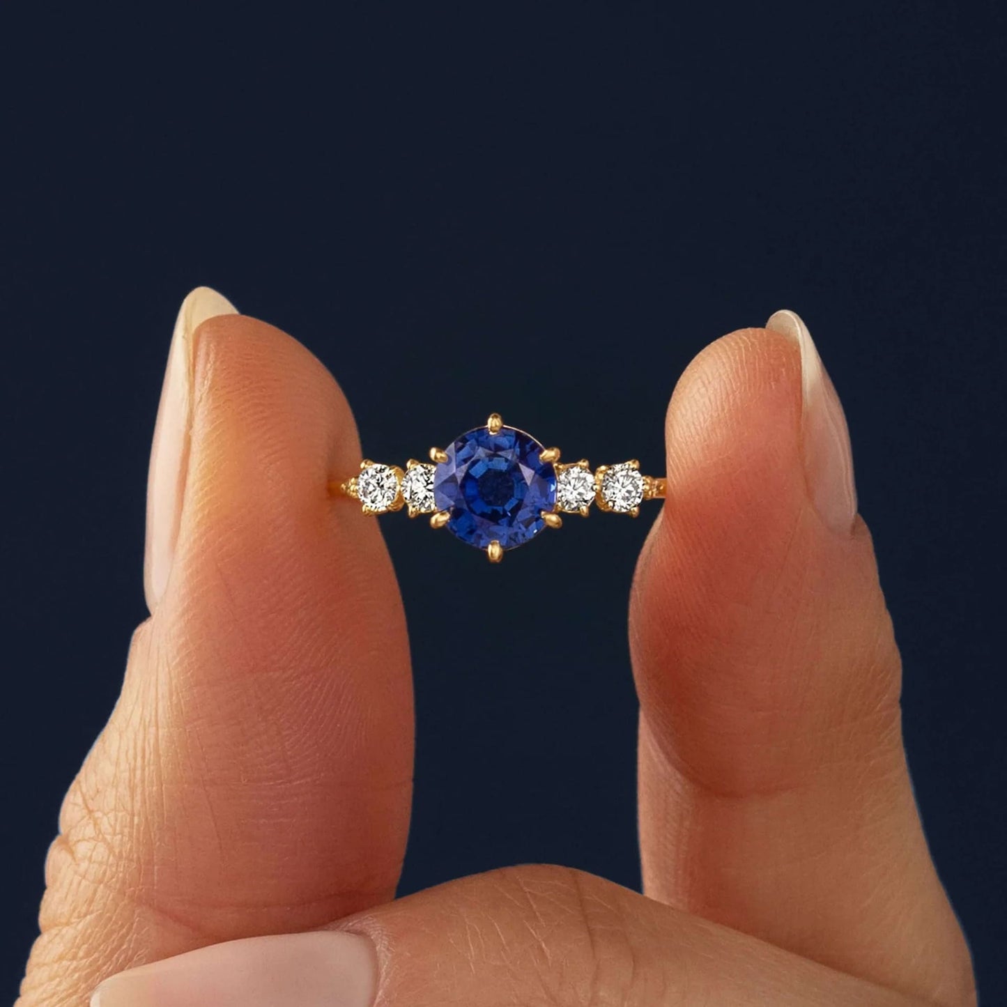 This engagement ring features 925 sterling silver with yellow gold plating, set with a deep blue round cut blue stone, exuding classic and noble elegance
