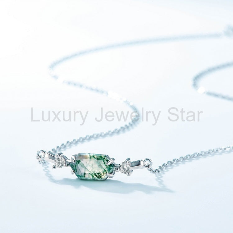 Green hexagon centerpiece with a curved silver-tone chain on a pale blue surface.
