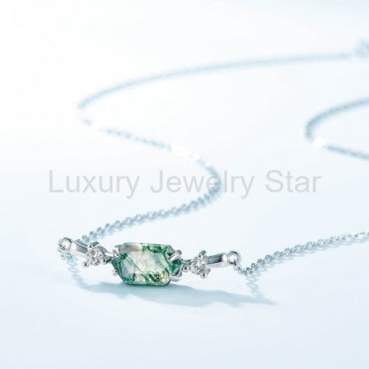 Green hexagon centerpiece with a curved silver-tone chain on a pale blue surface.
