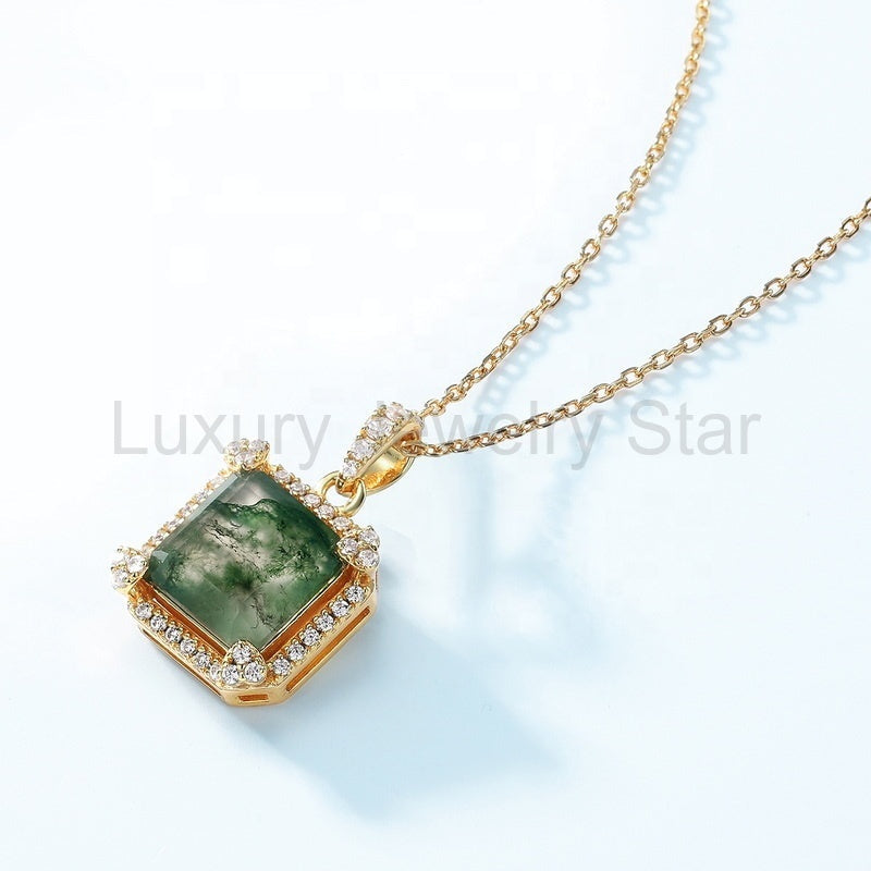 Square green-patterned pendant lying at an angle with a gold-tone chain and clear accents on the